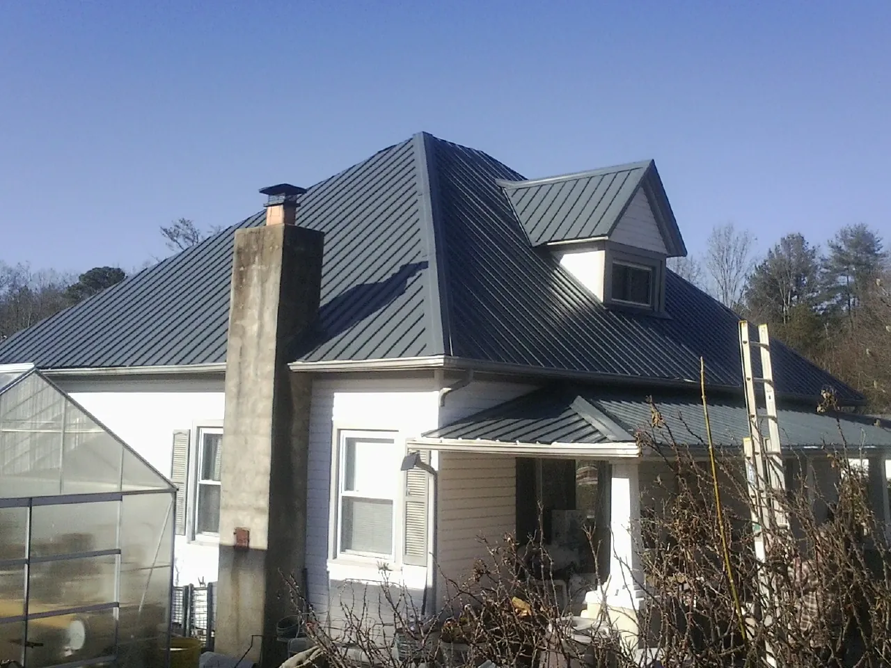 Dark blue standing seam metal roof on a white farmhouse with dormer — Slate & Tile Roof Repair by Roofing Brothers in Bolivia