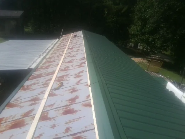 Old rusted panels beside newly installed green metal roofing — Wind Damage Roof Repair by Roofing Brothers in Bolivia
