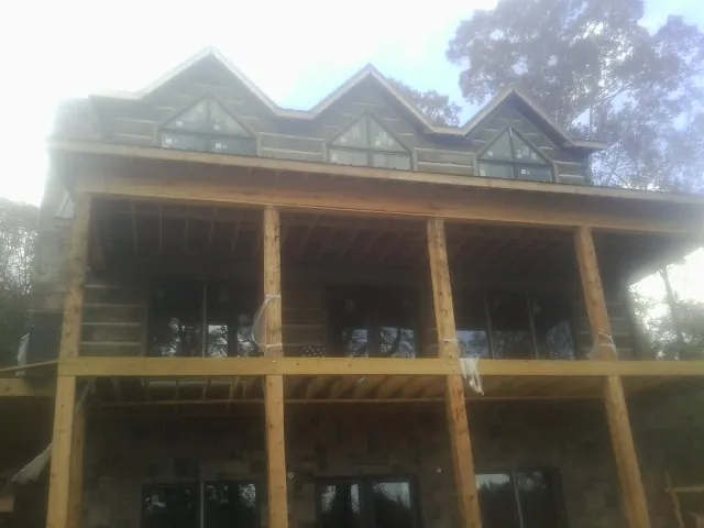 Dormers and porch framing on a large log home under construction — Roof Coating work by our crew in Bolivia