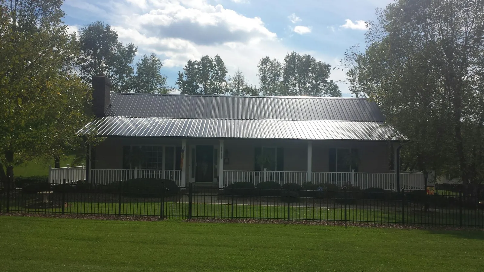 Gray metal roof on a brick ranch with a full width front porch — Gutter Guard Installation work by our crew in Bolivia