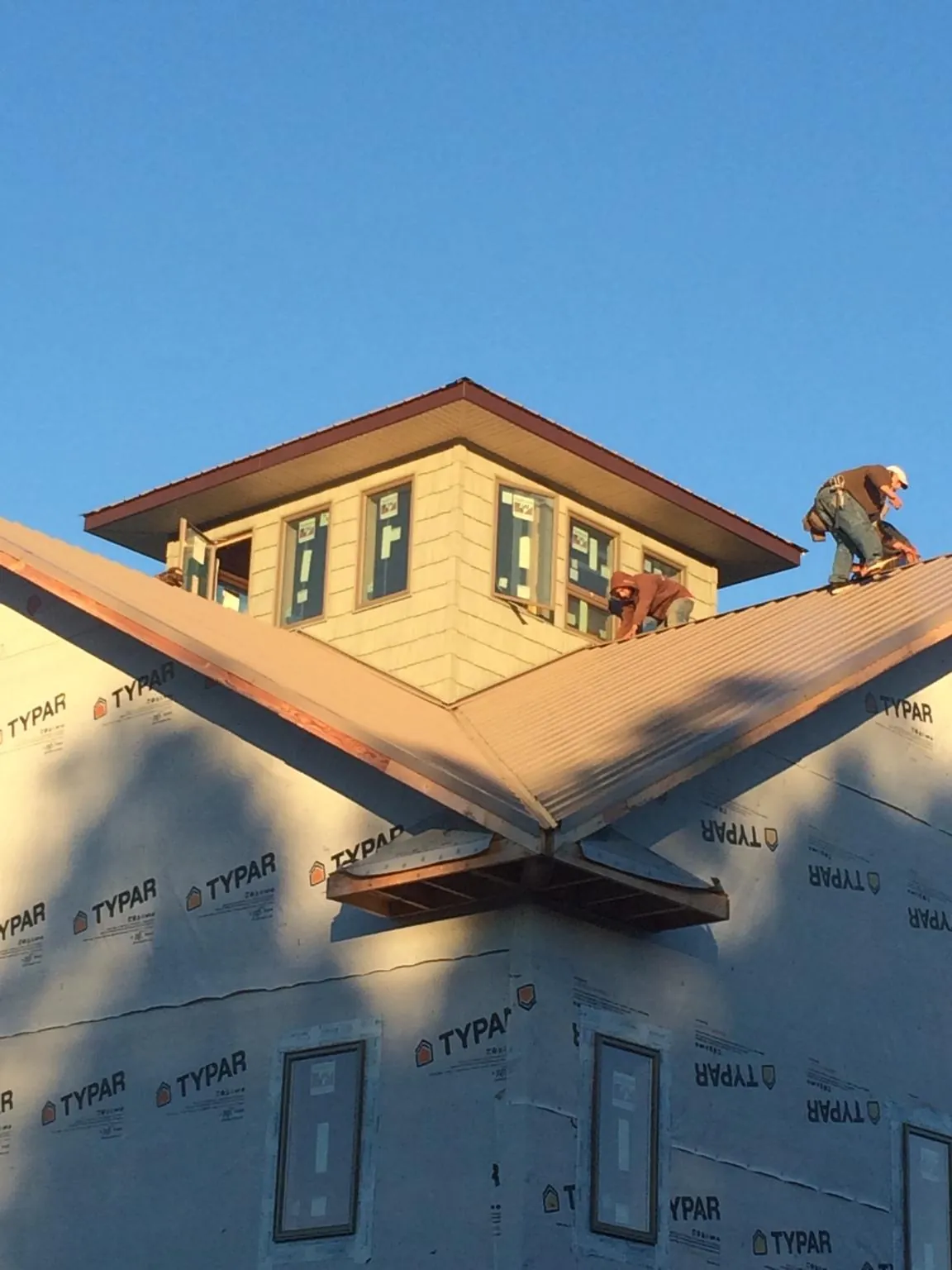 Roofers working around a rooftop cupola on a new metal roof at sunset — Roof Waterproofing in Bolivia by Roofing Brothers